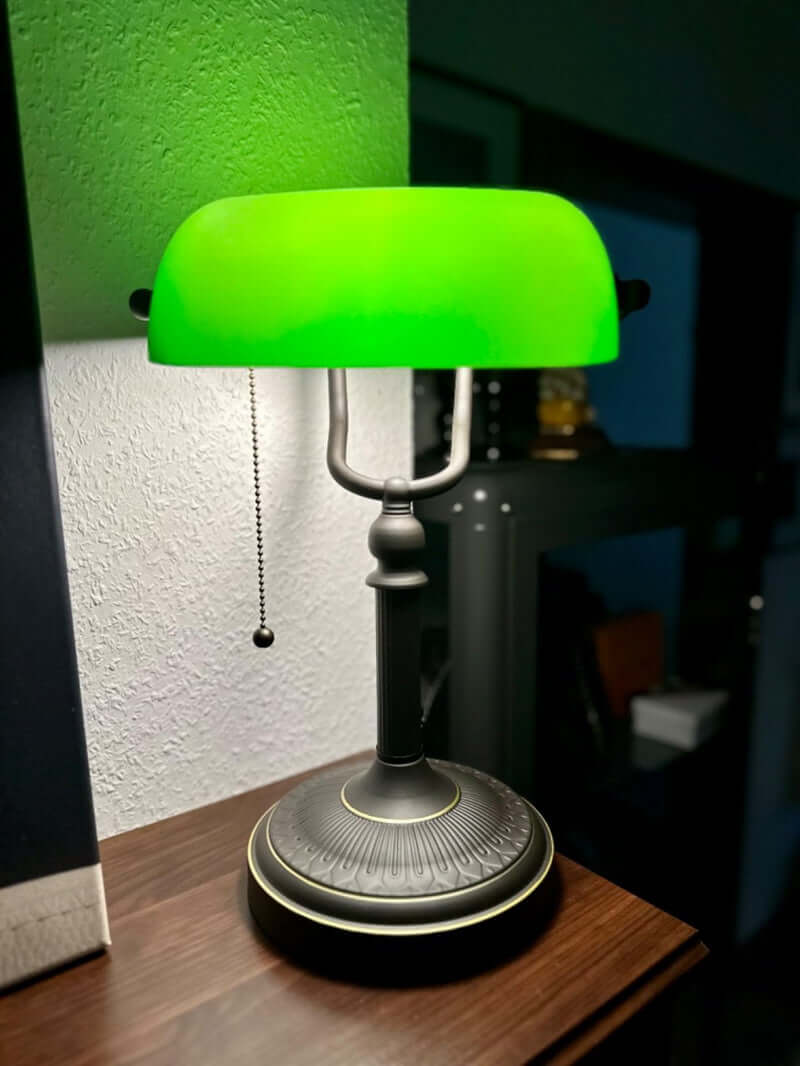 Antique Green Glass Desk Lamp with Pull Chain Switch,Banker Lamp on a wooden table, casting soft green light.