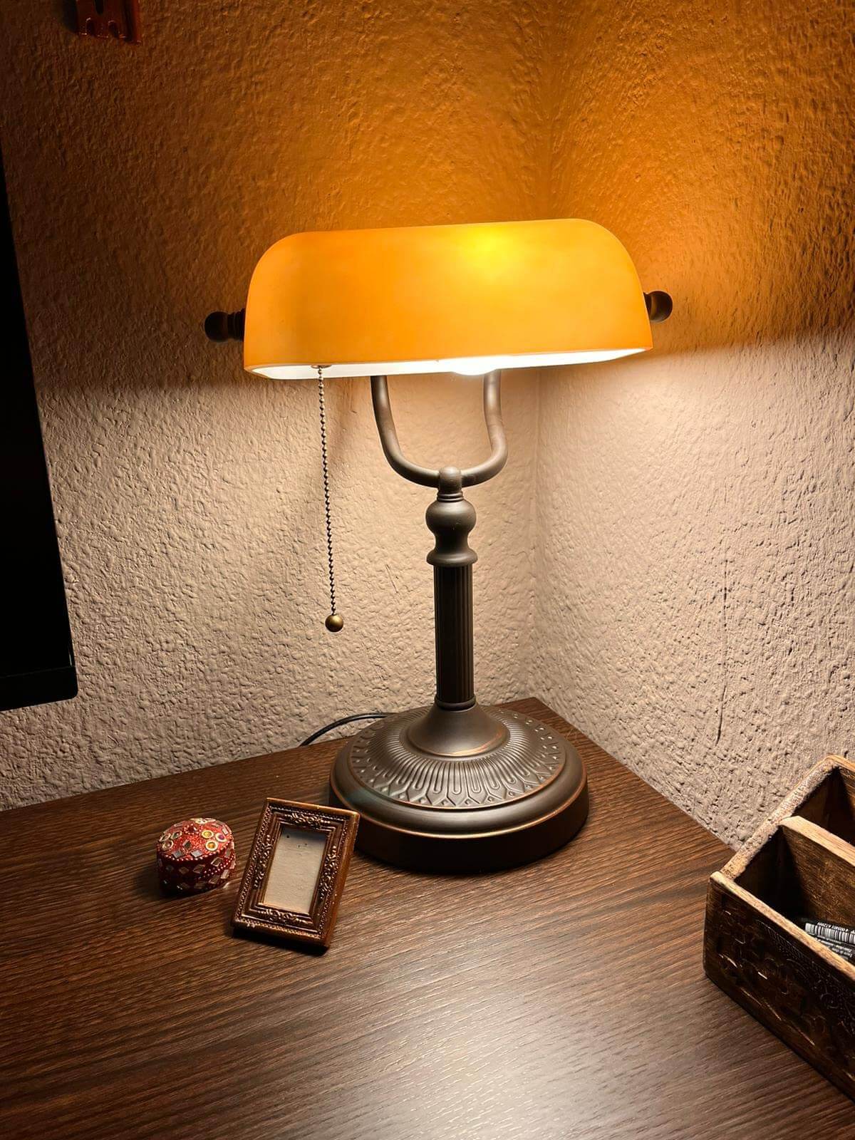 Newrays Matted Orange Glass Banker Desk Lamp with warm light on a wooden table, showcasing its elegant design.
