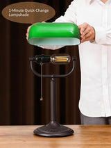 Antique green glass bankers desk lamp with a quick-change lampshade being adjusted by a person.