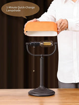 Person demonstrating the quick-change shade bankers desk lamp with an orange lampshade.