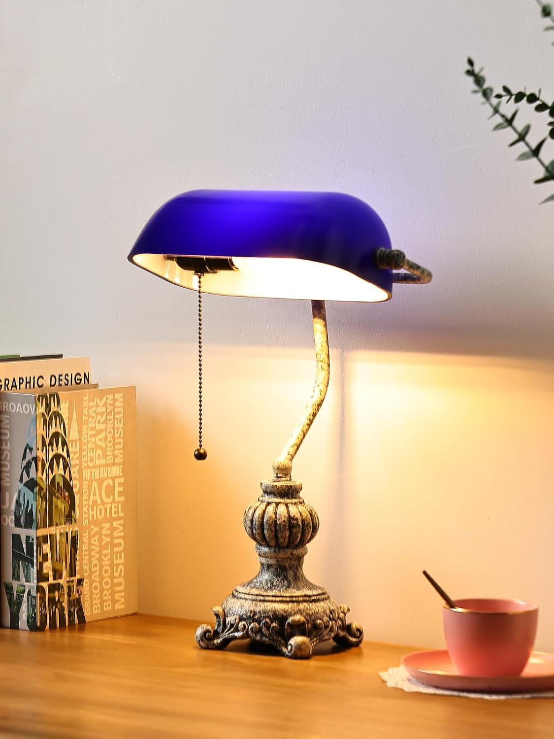 retro blue glass desk lamp on a wooden table with books and a cup