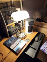 Matted White Glass Banker Lamp ,Sand Nickel Base on a desk with a book and desk organizer.