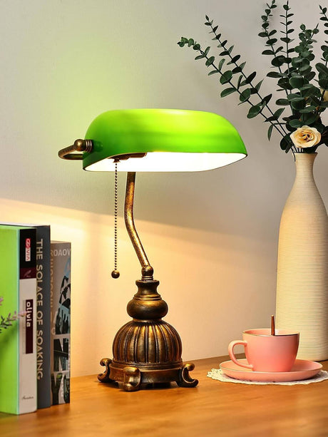 retro green glass desk lamp on a wooden table, with books and a teacup, adding vintage charm to the workspace.